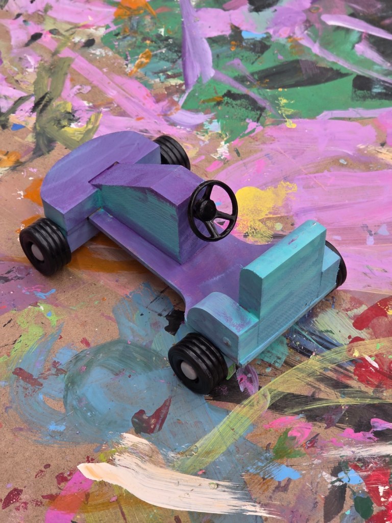 Finished wooden race car painted purple and turquoise